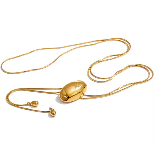 A gold necklace with a large, polished oval pendant suspended from a delicate snake chain, shown on a clean white background.