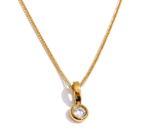 A gold chain necklace with a small round bezel-set clear gemstone pendant, shown on a plain white background.
