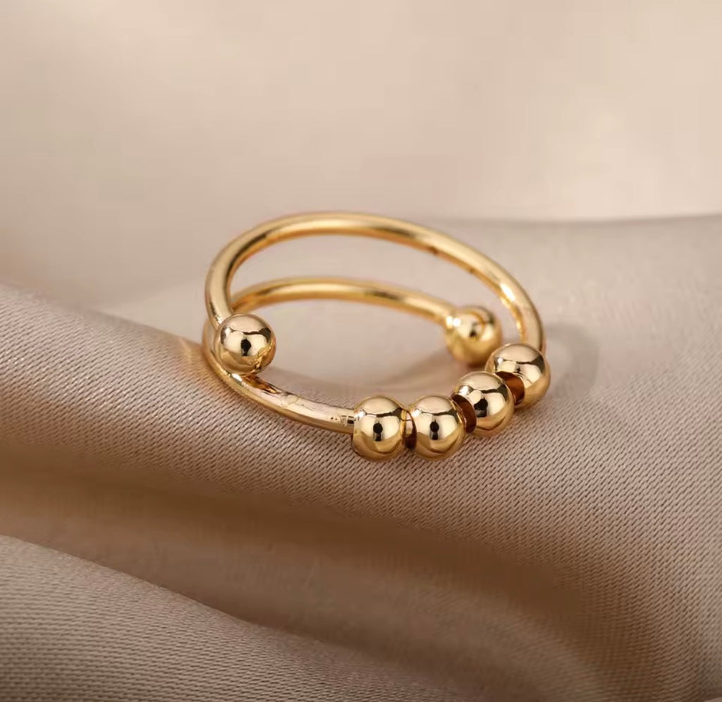 Anti-Anxiety Spinner Ring  Gold ring with bead accents on a beige fabric background
