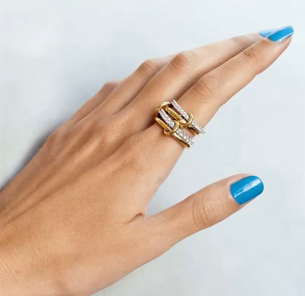 Hand wearing The Harmony Ring Set with blue nail polish on a light background