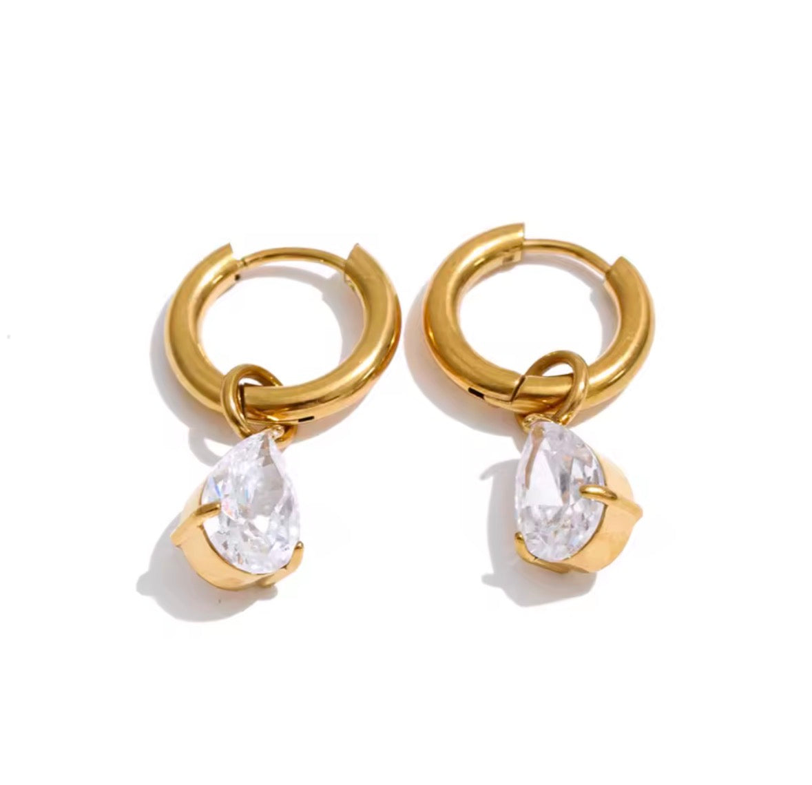 A pair of gold huggie hoop earrings with teardrop-shaped clear gemstones, displayed on a clean white background.