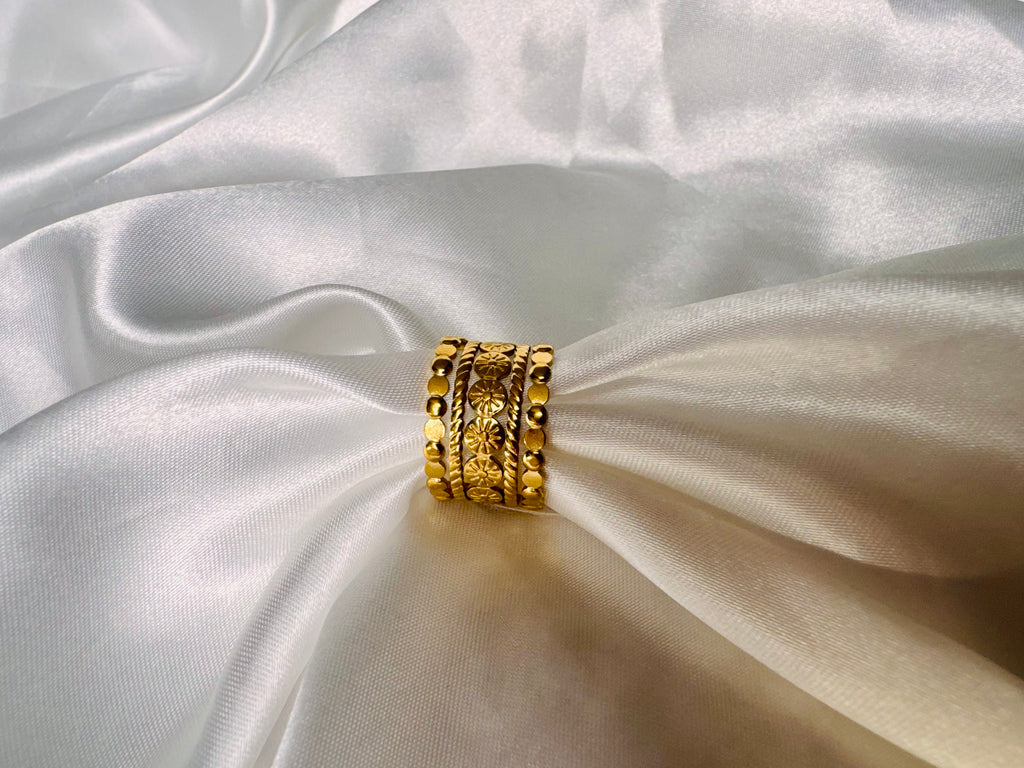 The Alessia Ring Gold rings stacked on a white fabric surface