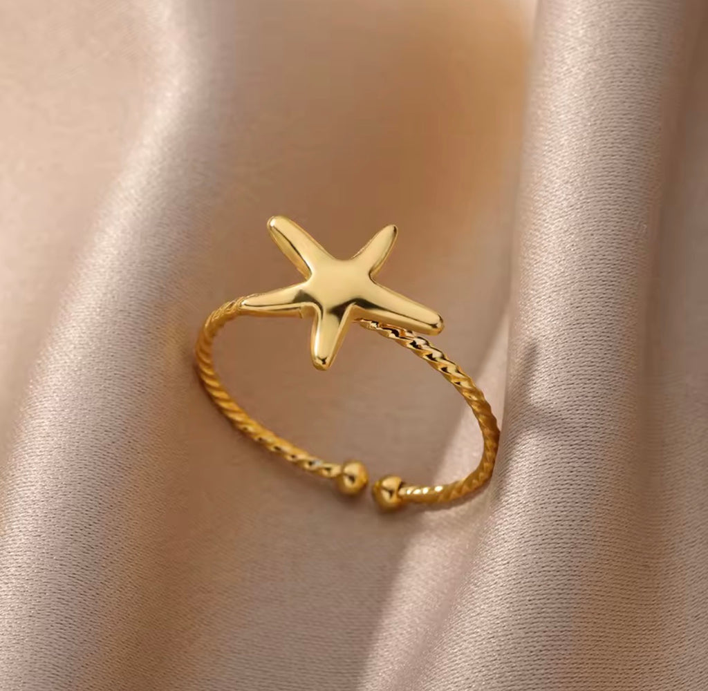 The Amalina Ring  Gold starfish ring on a beige fabric background