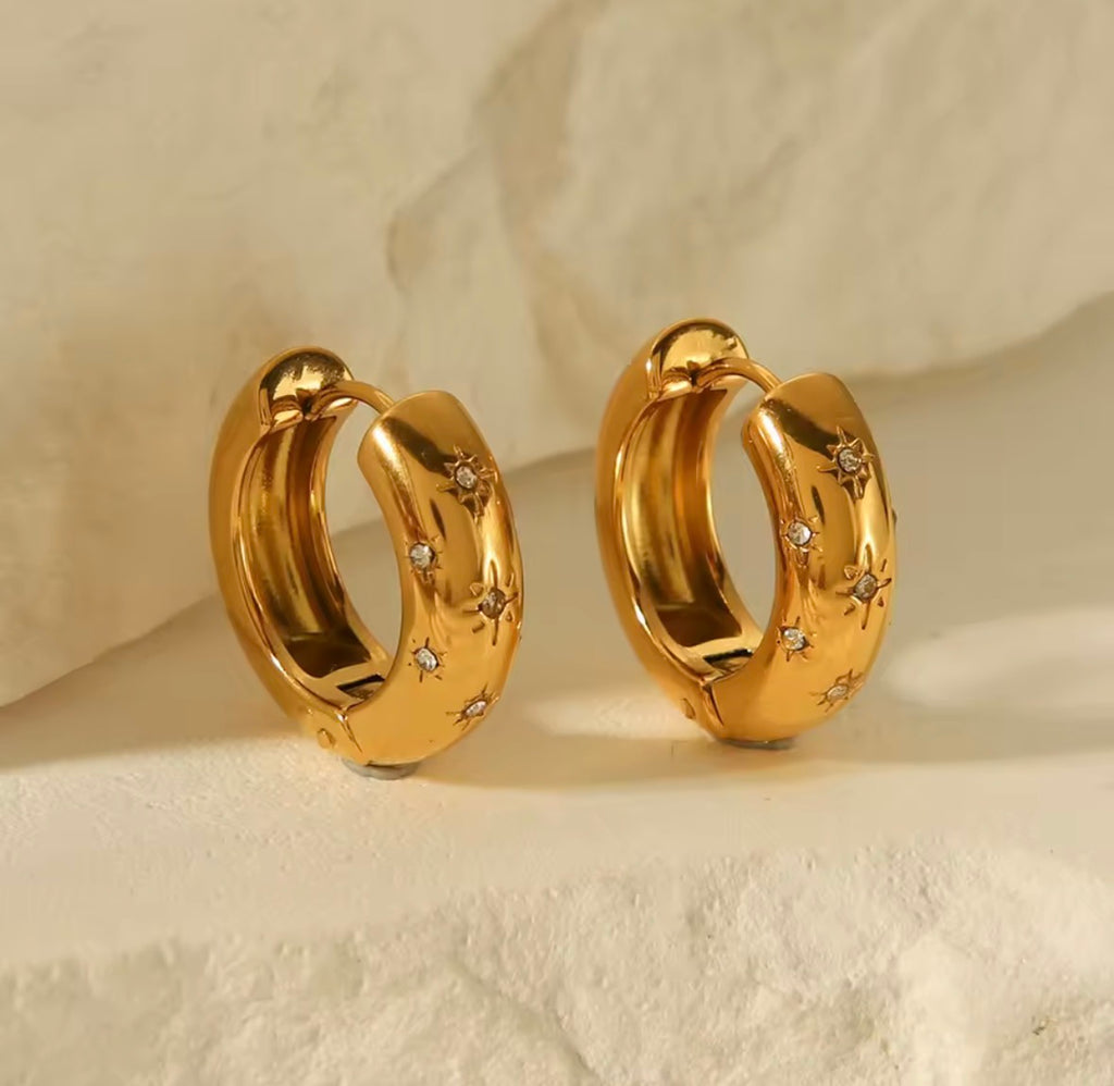 The Aurora Hoops Gold hoop earrings with embedded stones on a beige background