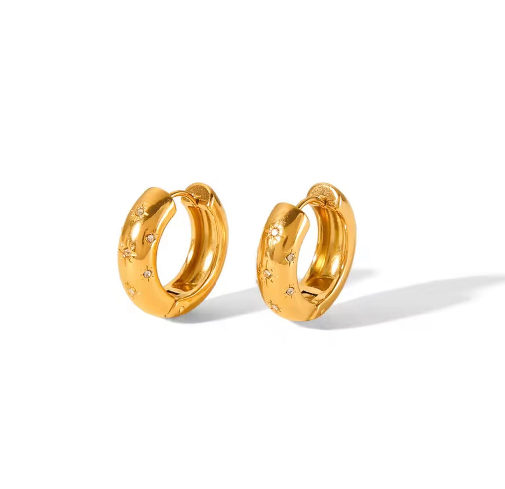 The Aurora Hoops Gold hoop earrings with star designs on a white background
