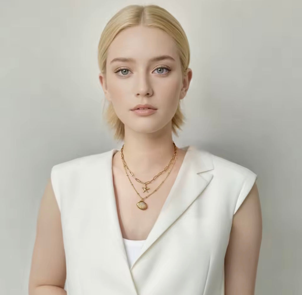 The Calypso Necklace: Woman wearing a white sleeveless blazer and gold jewelry against a plain background