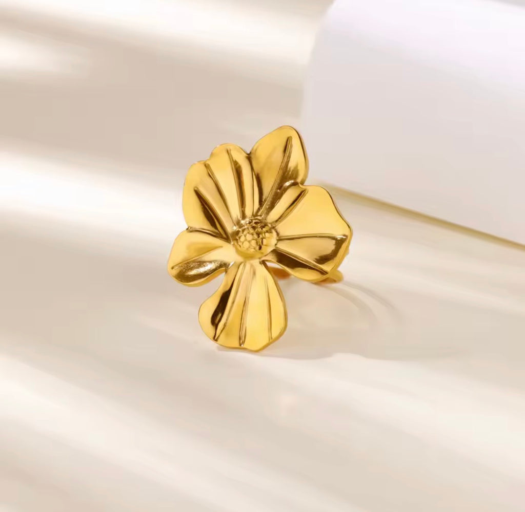 The Camellia Ring Gold flower-shaped earring on a soft beige background