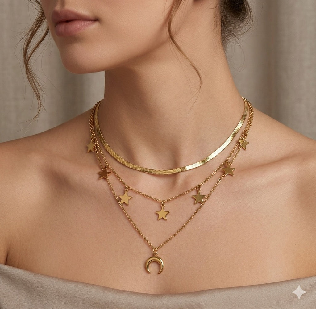 The Celestia Necklace:   Close-up of a person wearing a gold necklace with star pendants and a crescent moon charm.