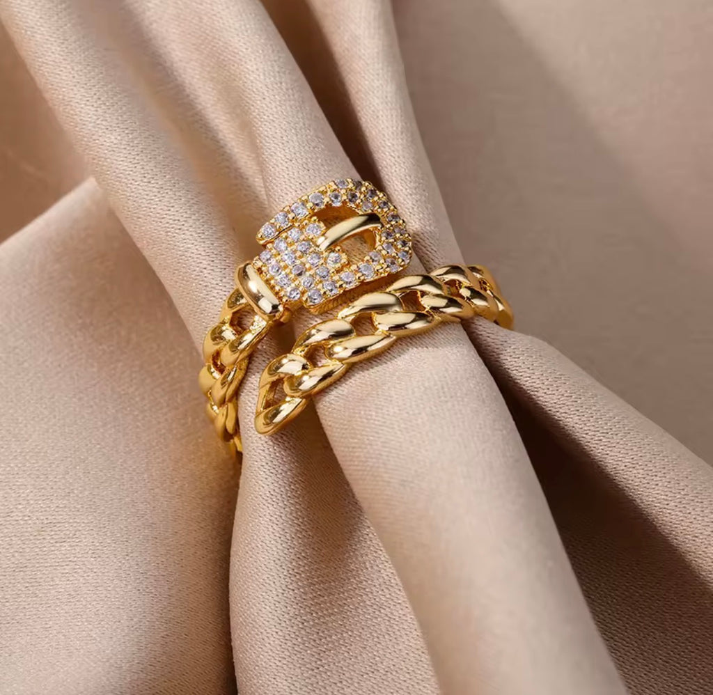 The Cintra Ring with chain design on a beige fabric background