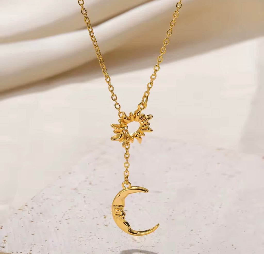 The Eclipse Necklace Gold necklace with sun and moon pendants on a light background