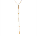 The Elisse Necklace A gold Y-shaped lariat necklace featuring three elongated cylindrical bar charms and three small round bead charms on a delicate chain, displayed against a solid white background.