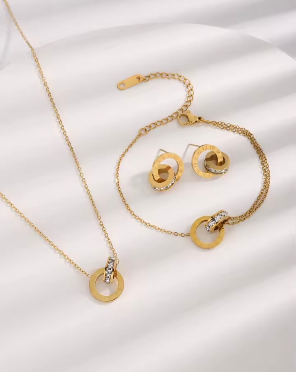 The Eterna Roman set including necklace, bracelet, and earrings on a white fabric background