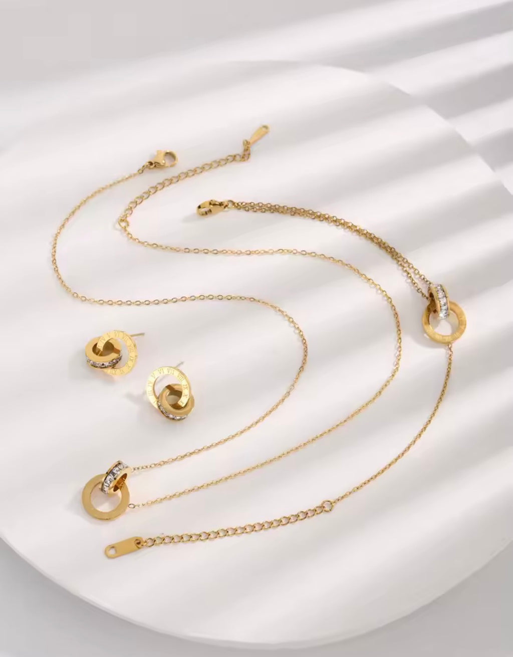 The Eterna Roman set including necklace, bracelet, and earrings on a white fabric background