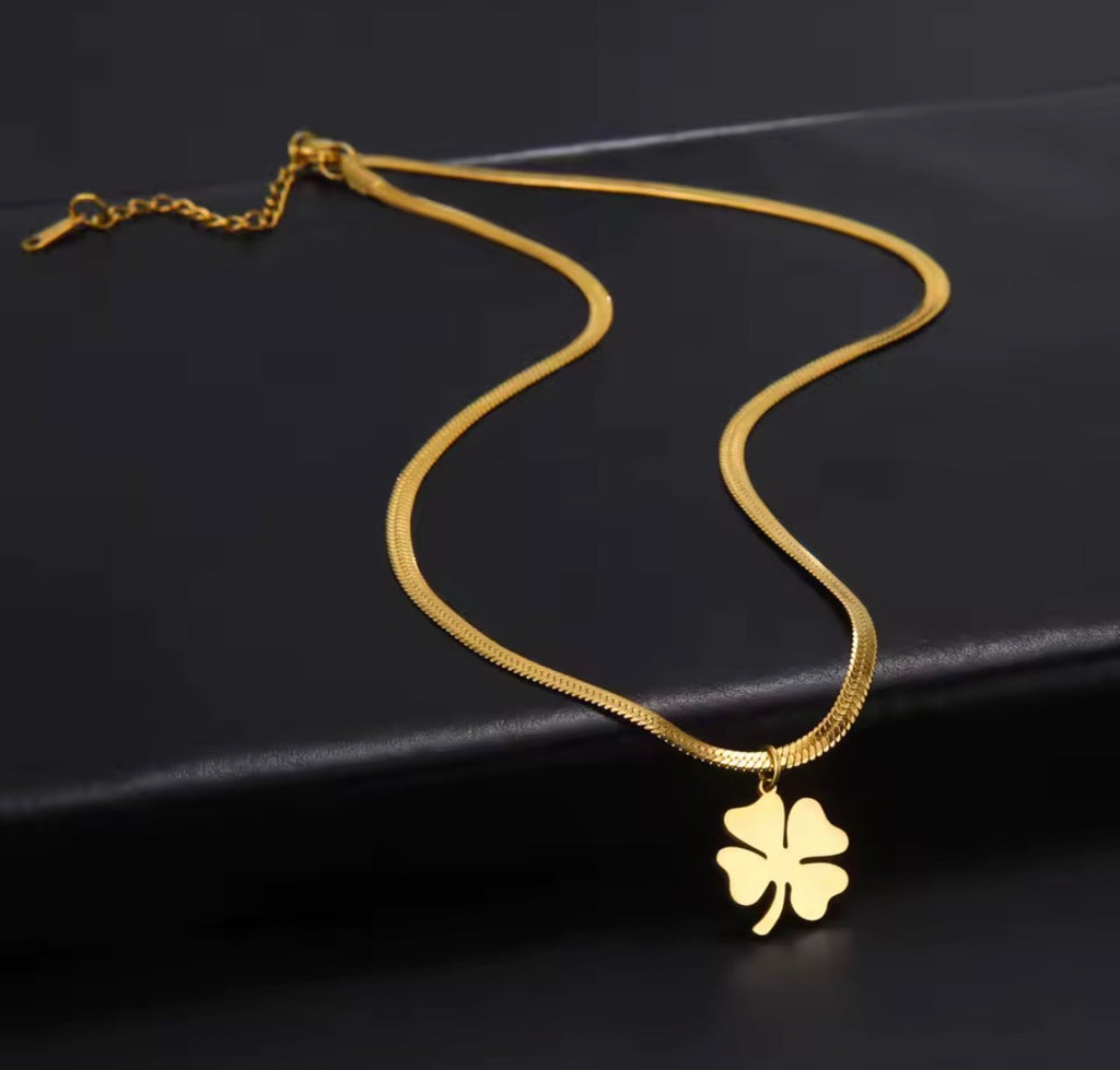 The Felicity Necklace with a four-leaf clover pendant on a black background