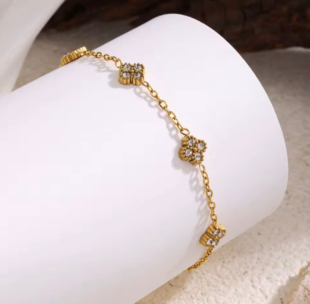 Shop The Florielle Bracelet – a delicate gold-tone stainless steel bracelet with sparkling cubic zirconia flowers. Adjustable, hypoallergenic and perfect for gifting.