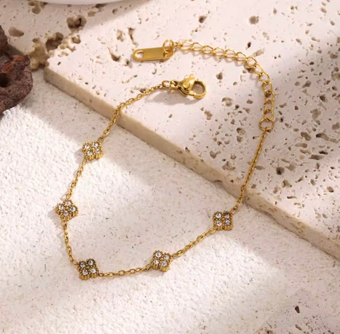 Shop The Florielle Bracelet – a delicate gold-tone stainless steel bracelet with sparkling cubic zirconia flowers. Adjustable, hypoallergenic and perfect for gifting.