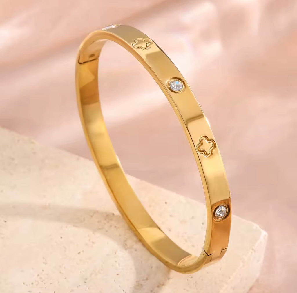 The Fortuna Clover bracelet with diamond accents on a soft pink background