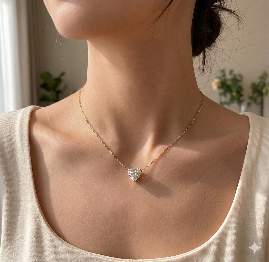 The Grace Necklace with a heart-shaped pendant, worn by a person in a neutral setting