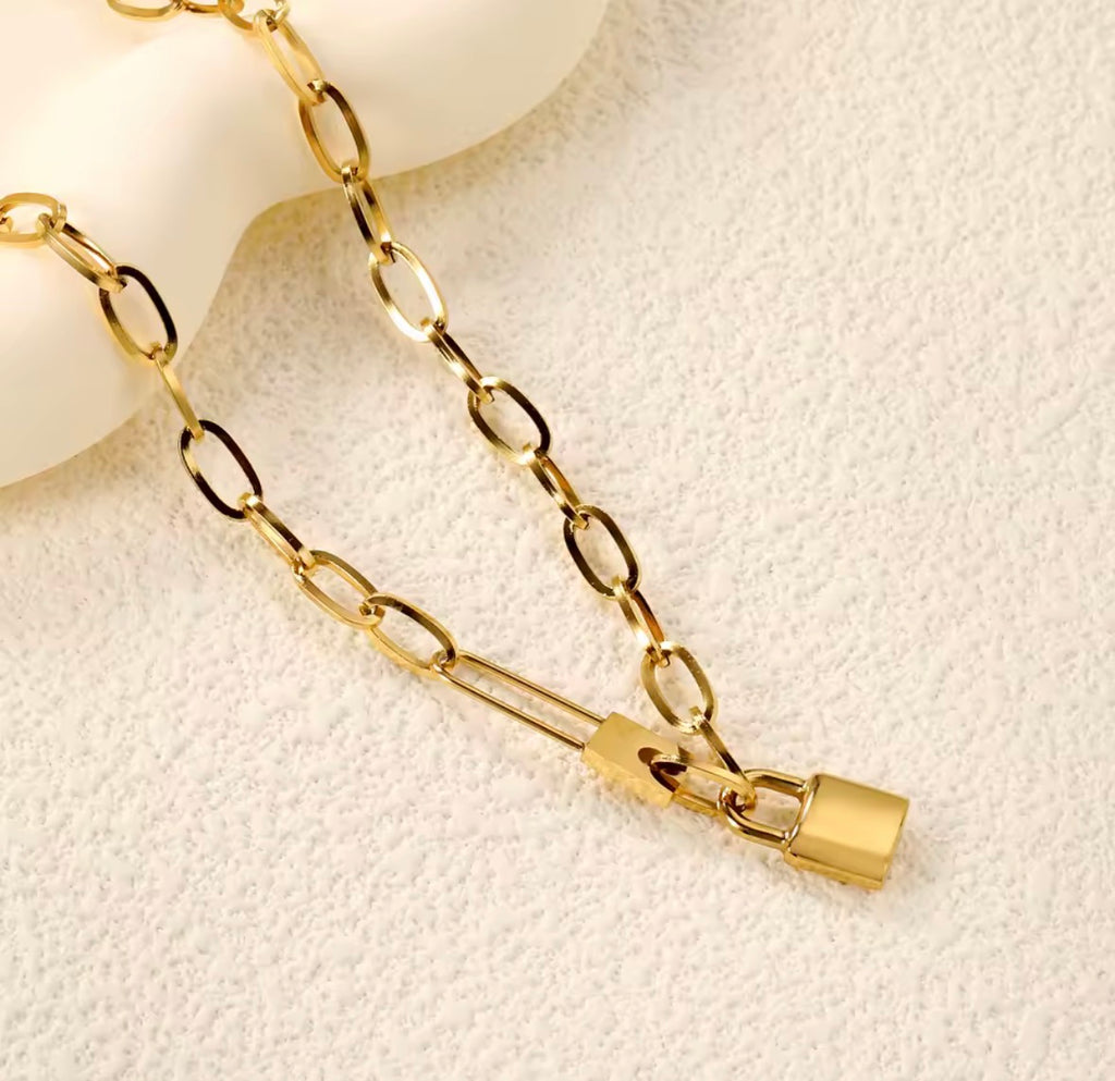 The Heartlock Necklace Gold chain necklace with a lock pendant on a light beige background