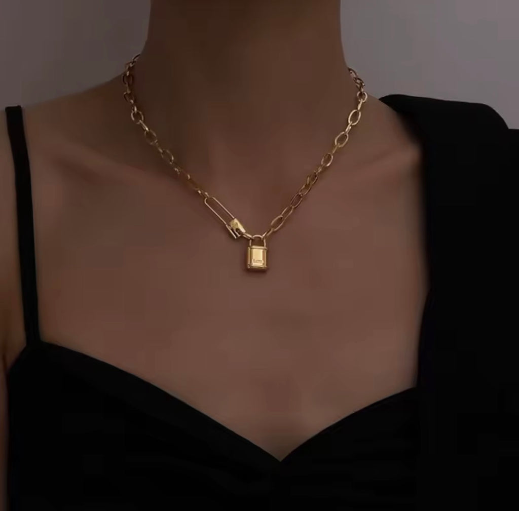 The Heartlock Necklace  Gold necklace with a pendant on a mannequin against a dark background
