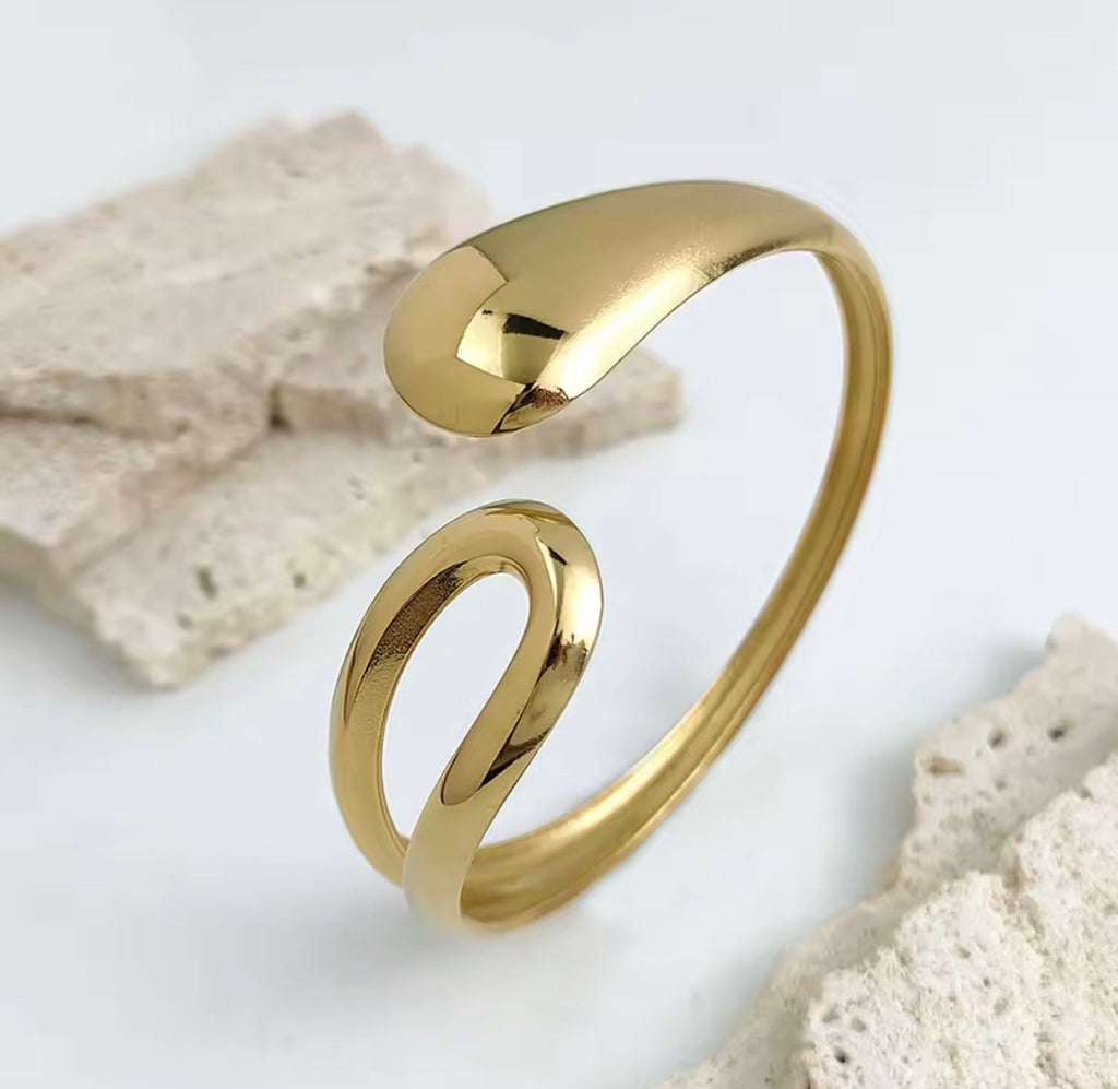 The Imperia Bangle Gold bracelet on a light gray background