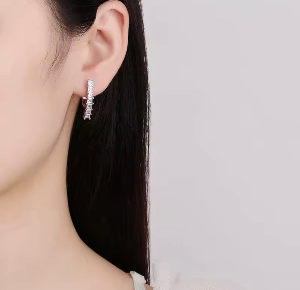 The Isabella Studs Close-up of a person wearing silver hoop earrings with a plain background