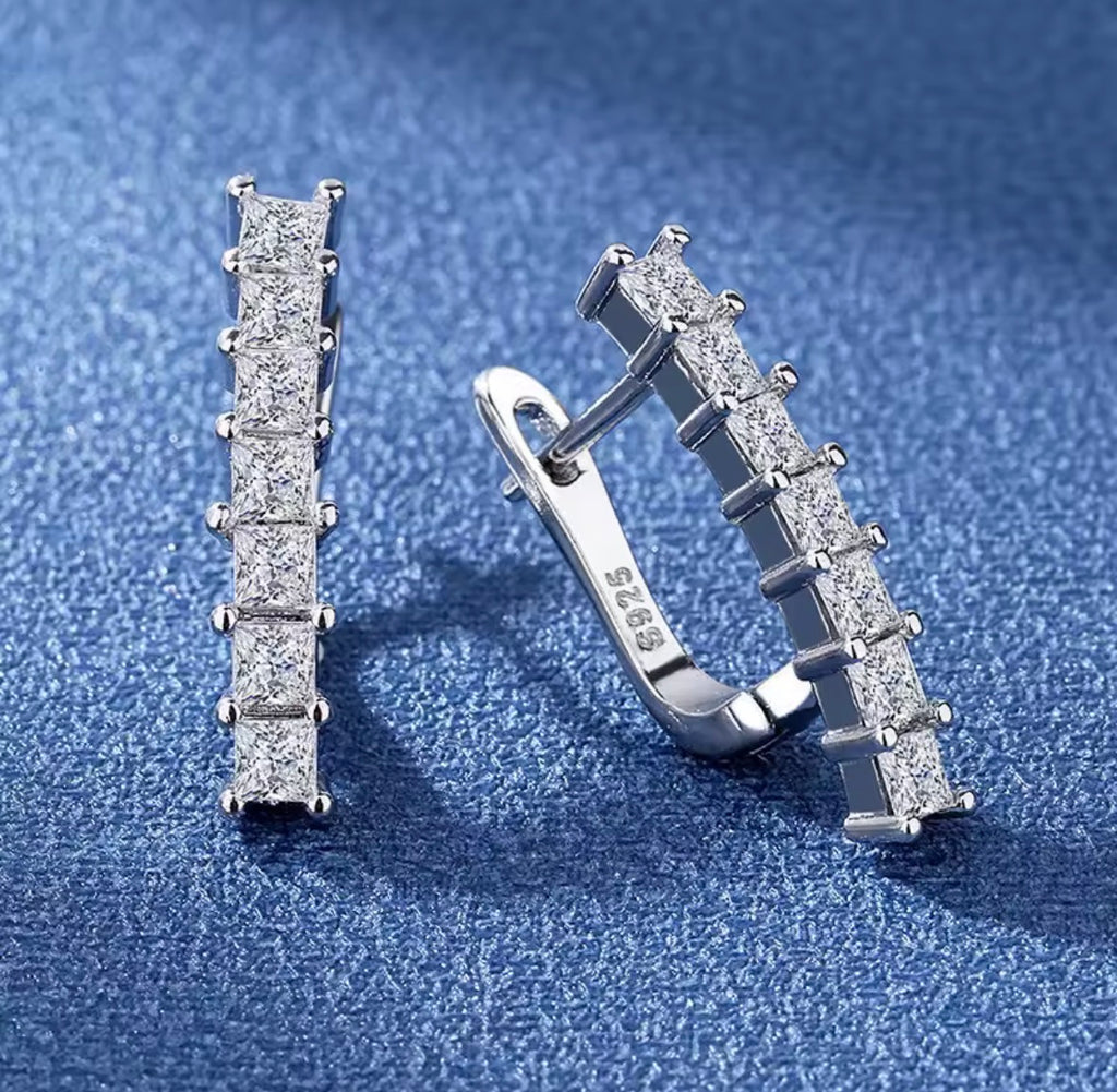 The Isabella Studs Silver earrings with gemstones on a blue textured background