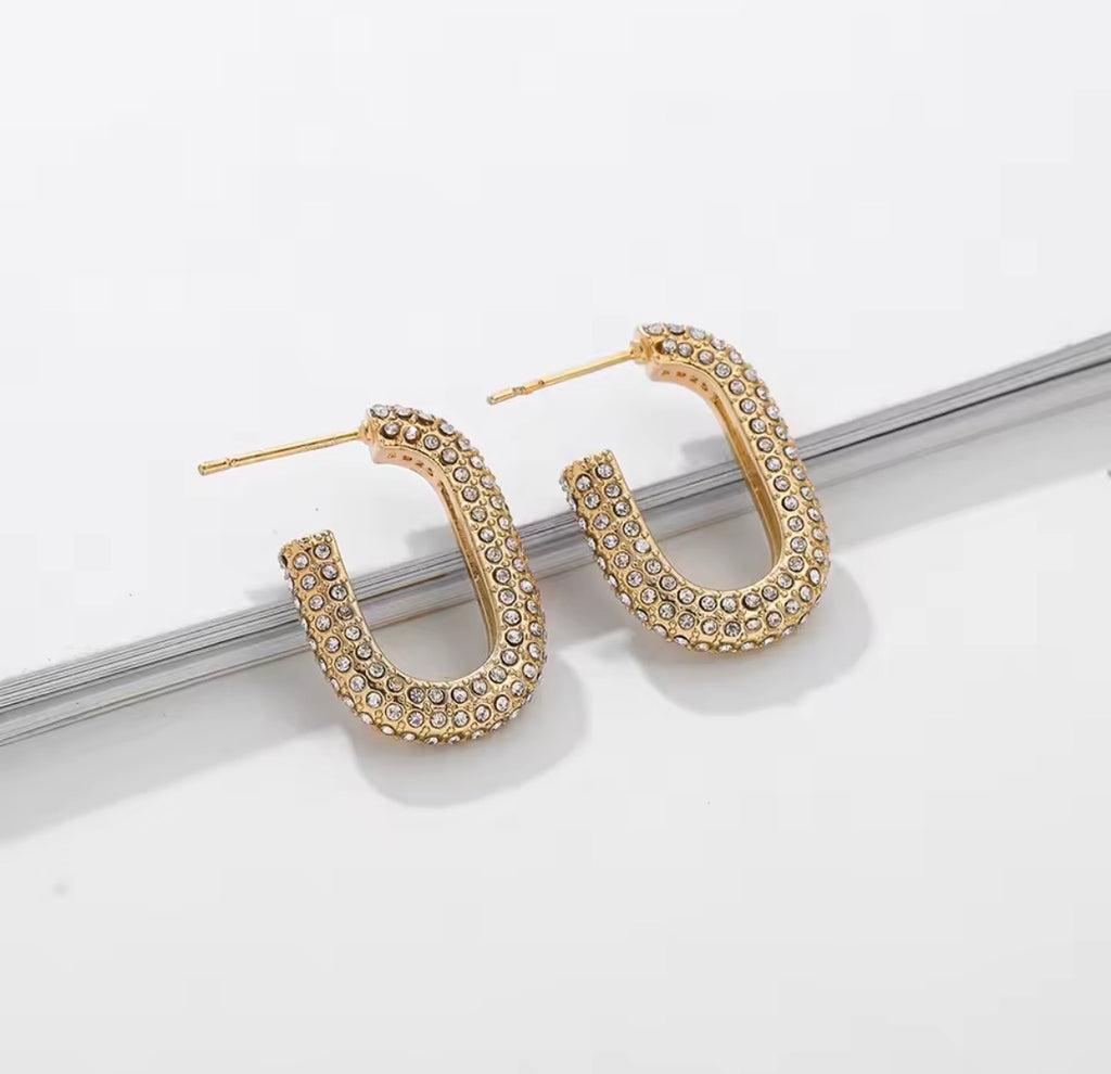 The Lyra Huggies Gold hoop earrings with embedded stones on a white surface