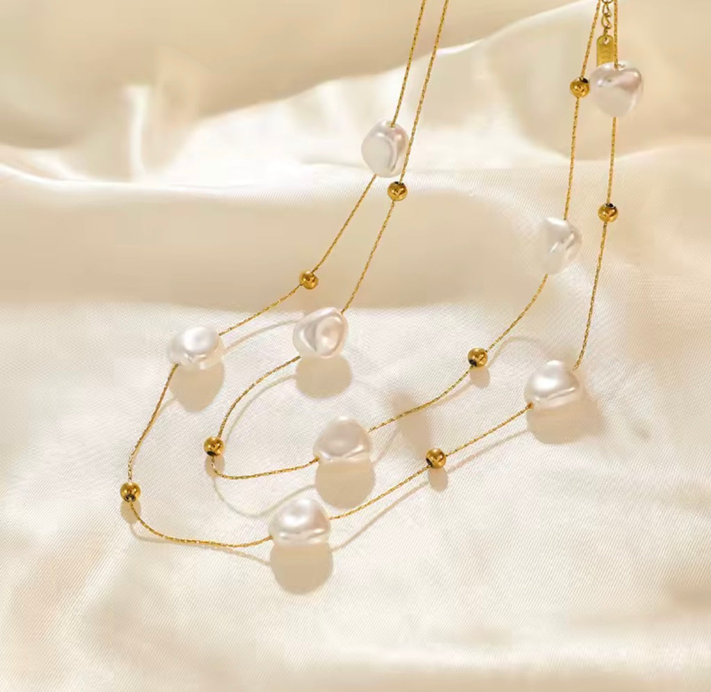 The Mirabelle Necklace  Pearl necklace with gold accents on a soft beige fabric background