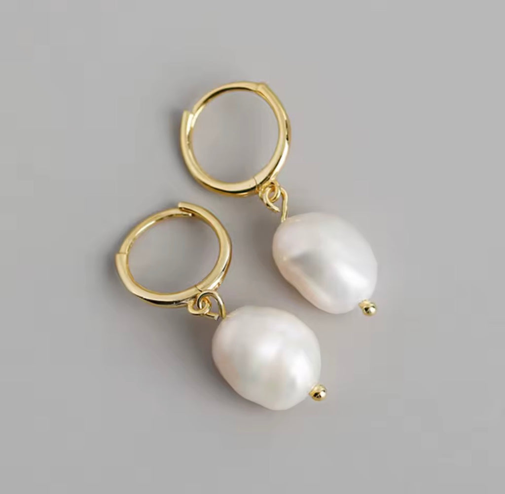 The Perlina Studs  Gold hoop earrings with white pearls on a gray background