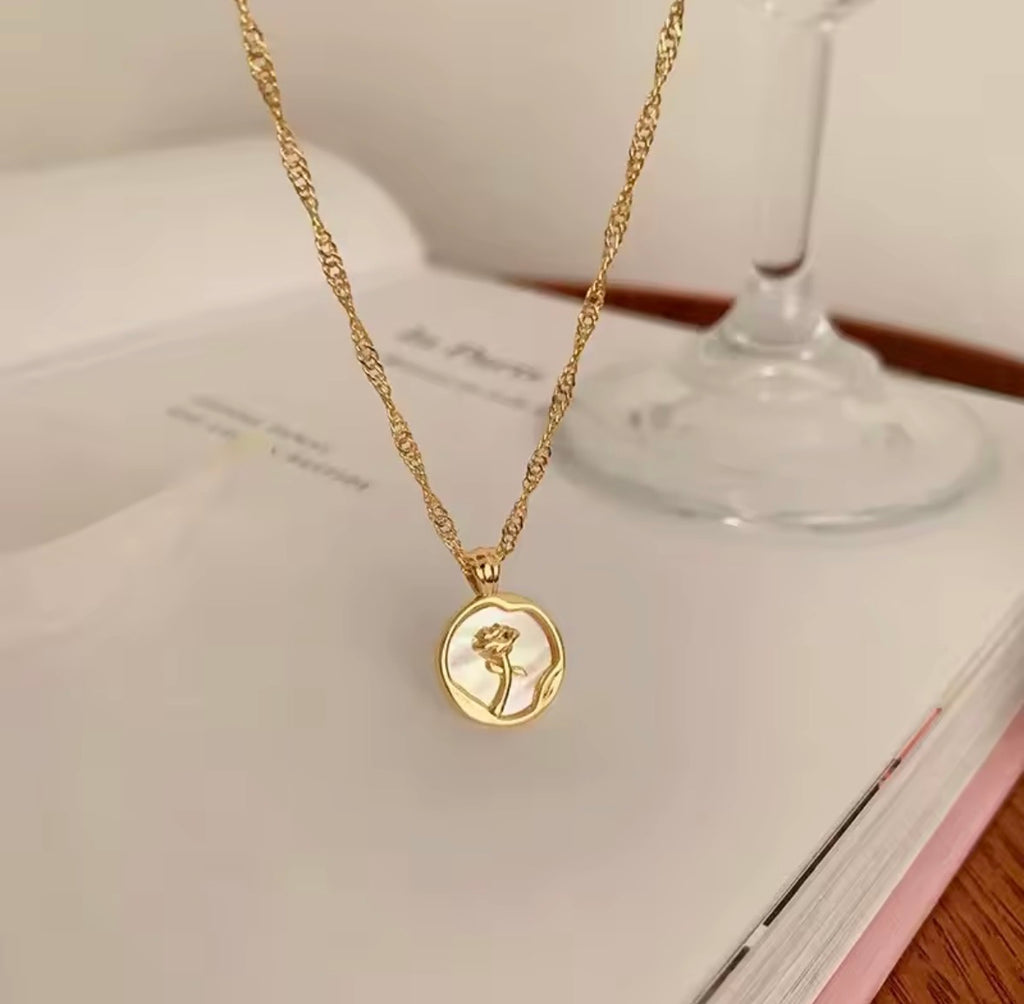 The Rosa del Mar necklace with a pendant on a book