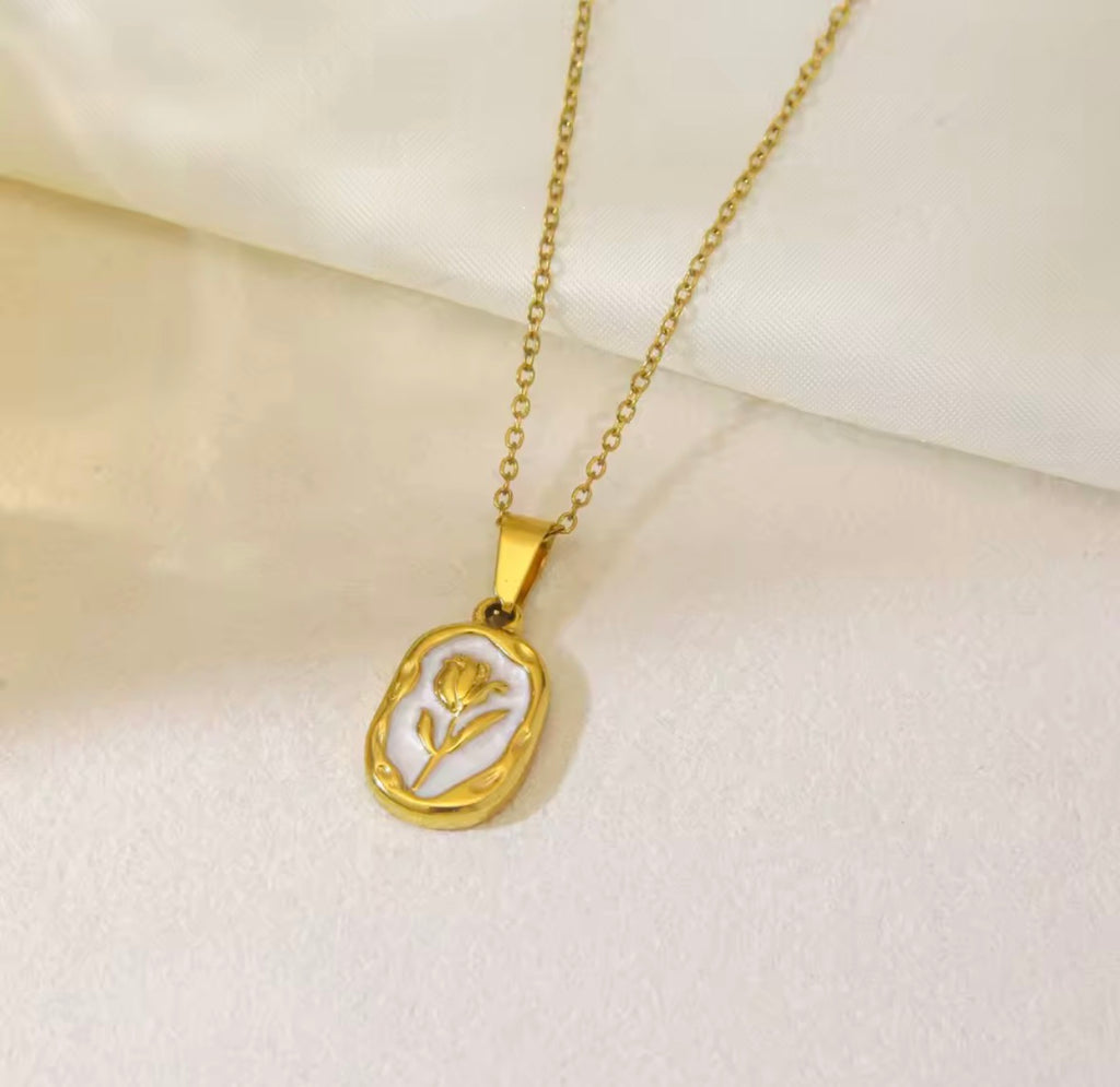 The Rosalie Necklace with a pendant featuring a floral design on a beige background