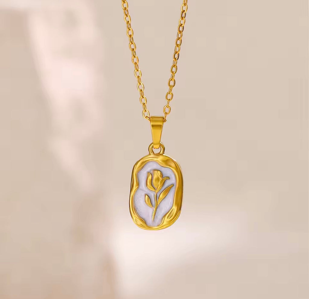 The Rosalie Necklace  with a pendant featuring a tulip design on a beige background