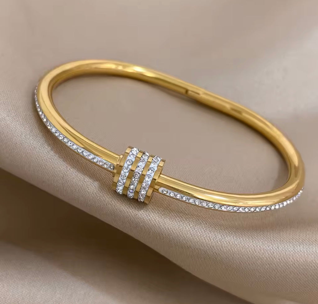  The Selene Bangle  Gold bracelet with diamond accents on a beige fabric background