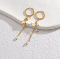 The Stella Earrings are gold hoop earrings with star and bead details on a white surface