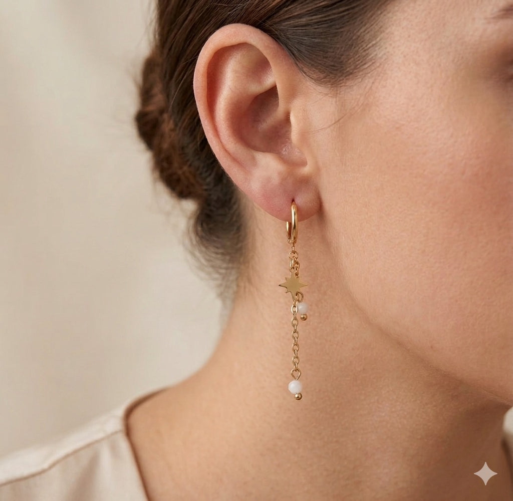 The Stella earrings Gold hoop earring with pearl drop worn by a person against a neutral background
