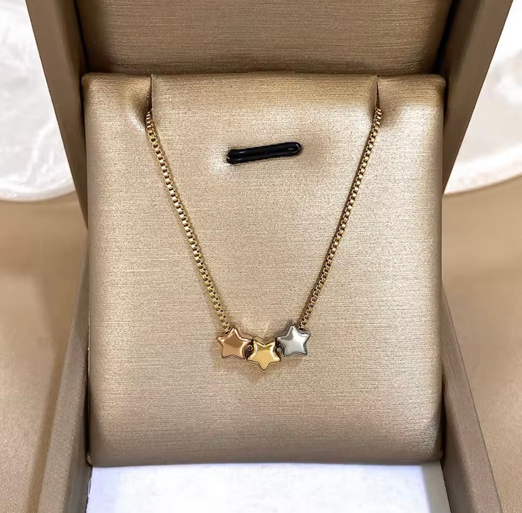 The Twinkle Necklace:  Gold necklace with star pendants in a beige jewelry box