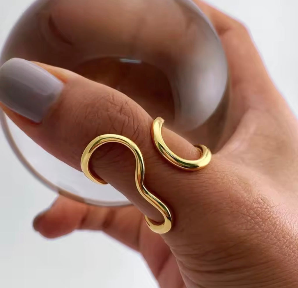The Vaela Ring Gold ring on a finger with a plain background