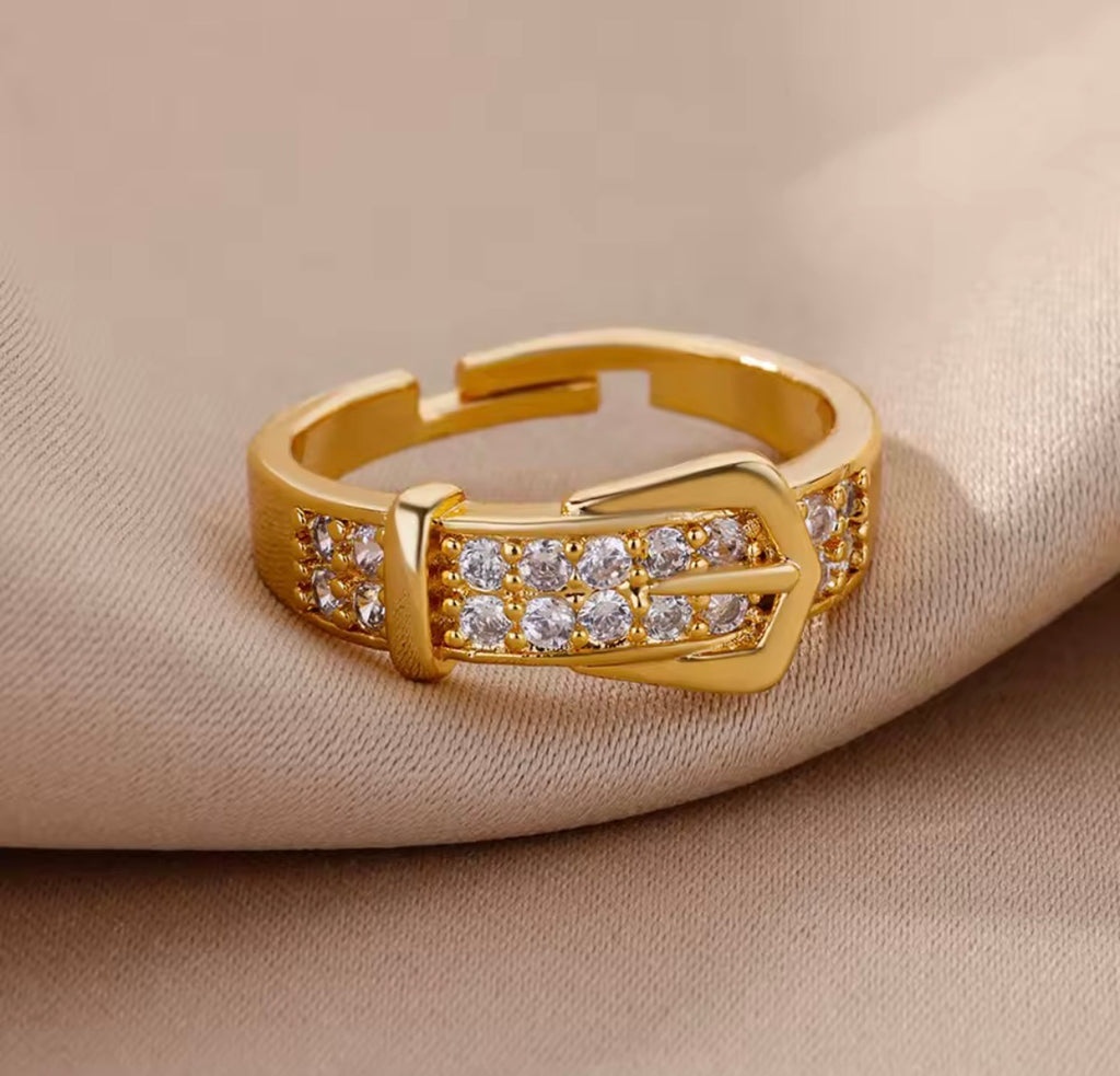 The Vincenza Ring with diamond buckle design on a beige background