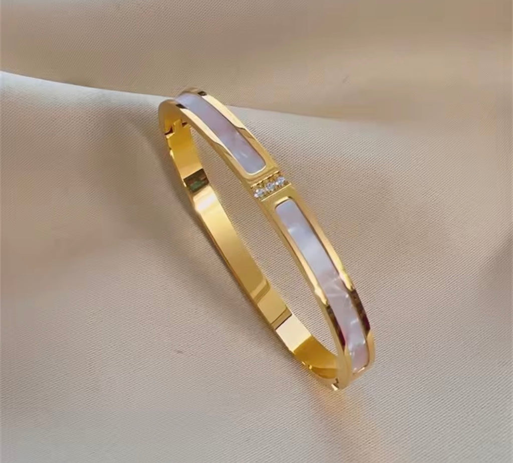 The Vivara Bangle bracelet with a white stone on a beige fabric background