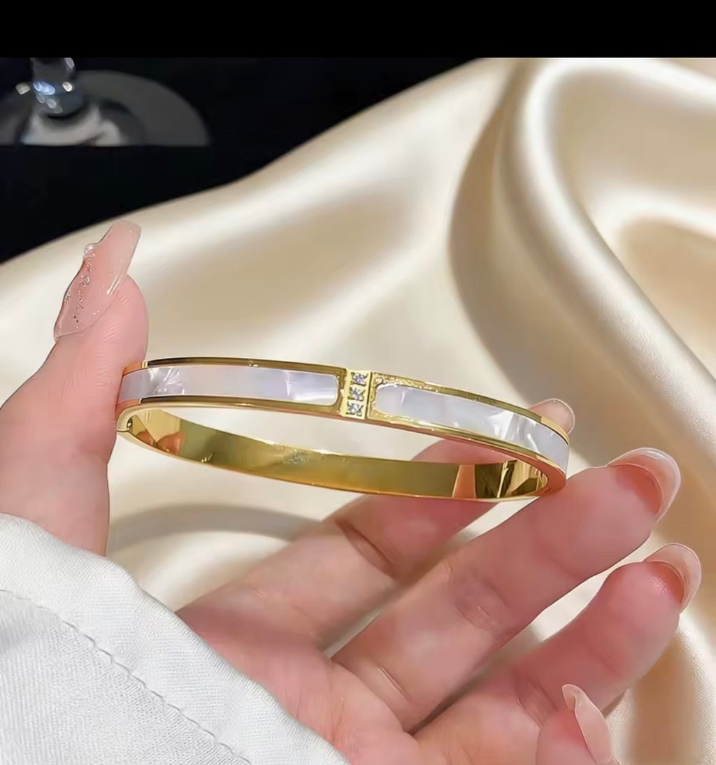 The Vivara  bangle held by a hand on a beige fabric background