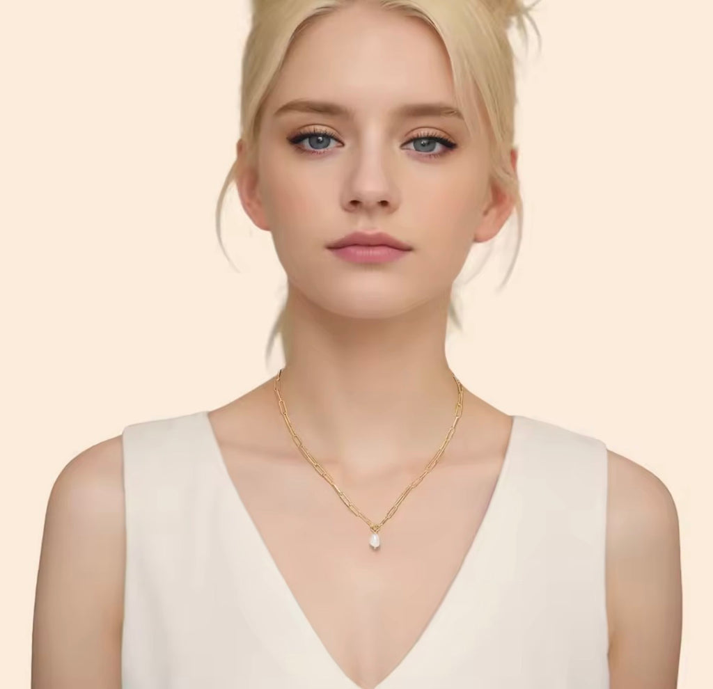 The Vivienne Pearl   Woman wearing a gold necklace with a pearl pendant on a beige background
