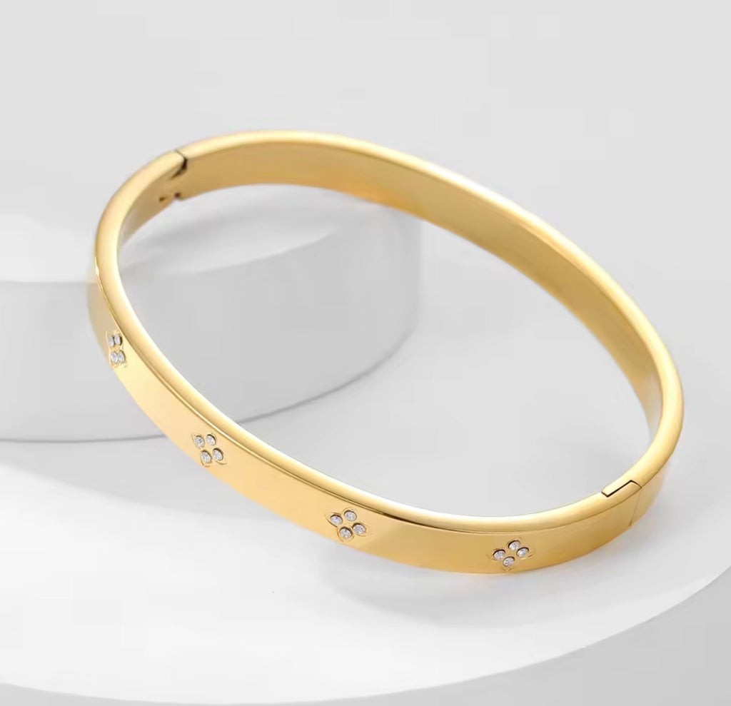 The Zaria Cuff bracelet with floral engravings on a light gray background