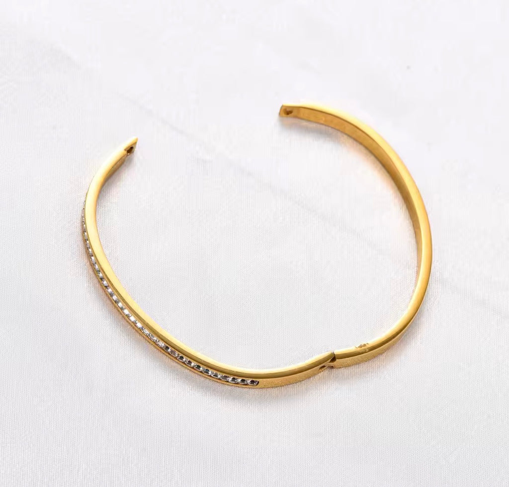 The Éclat Cuff bangle with embedded stones on a white background