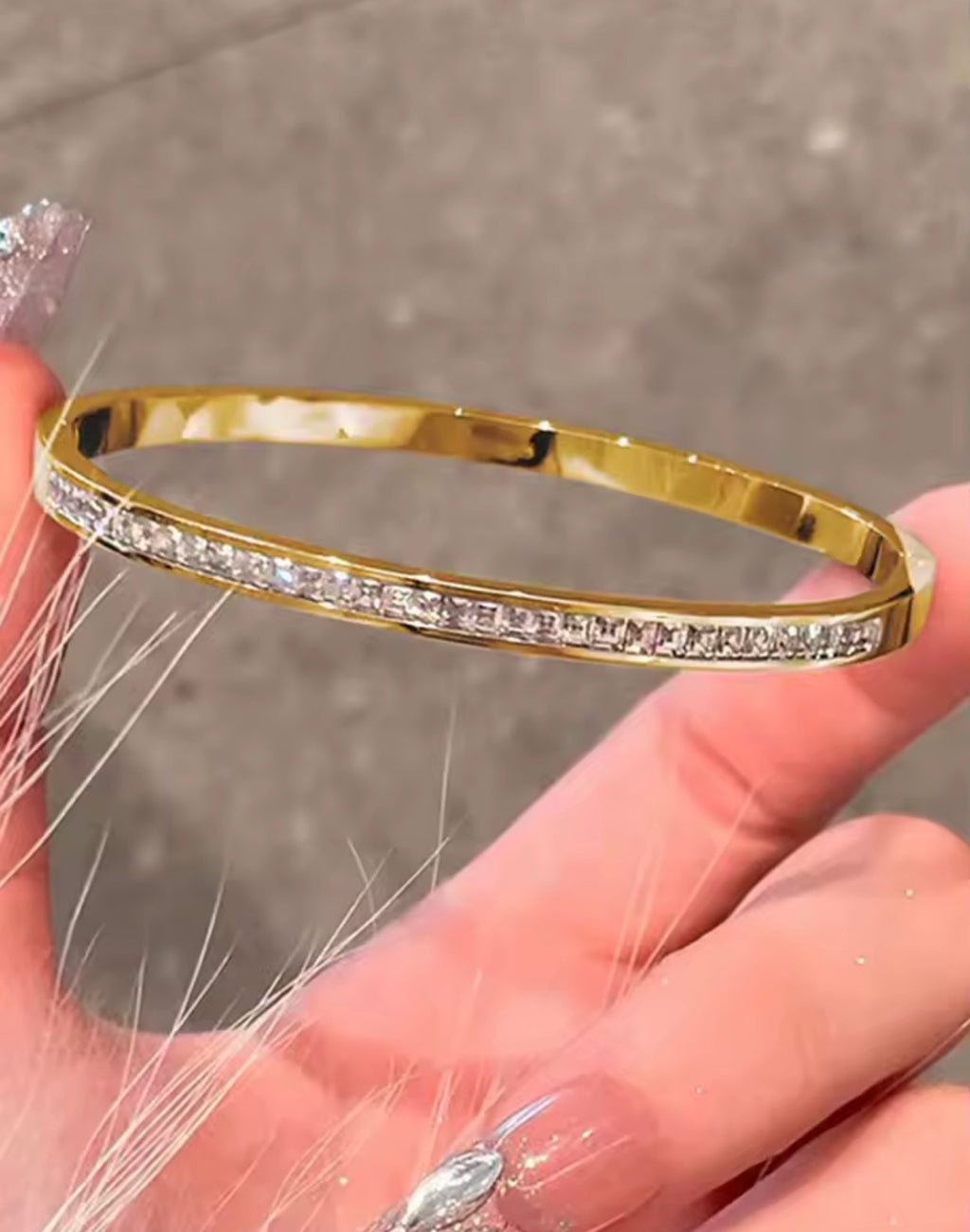 The Éclat Cuff bracelet with diamonds held in a hand against a neutral background