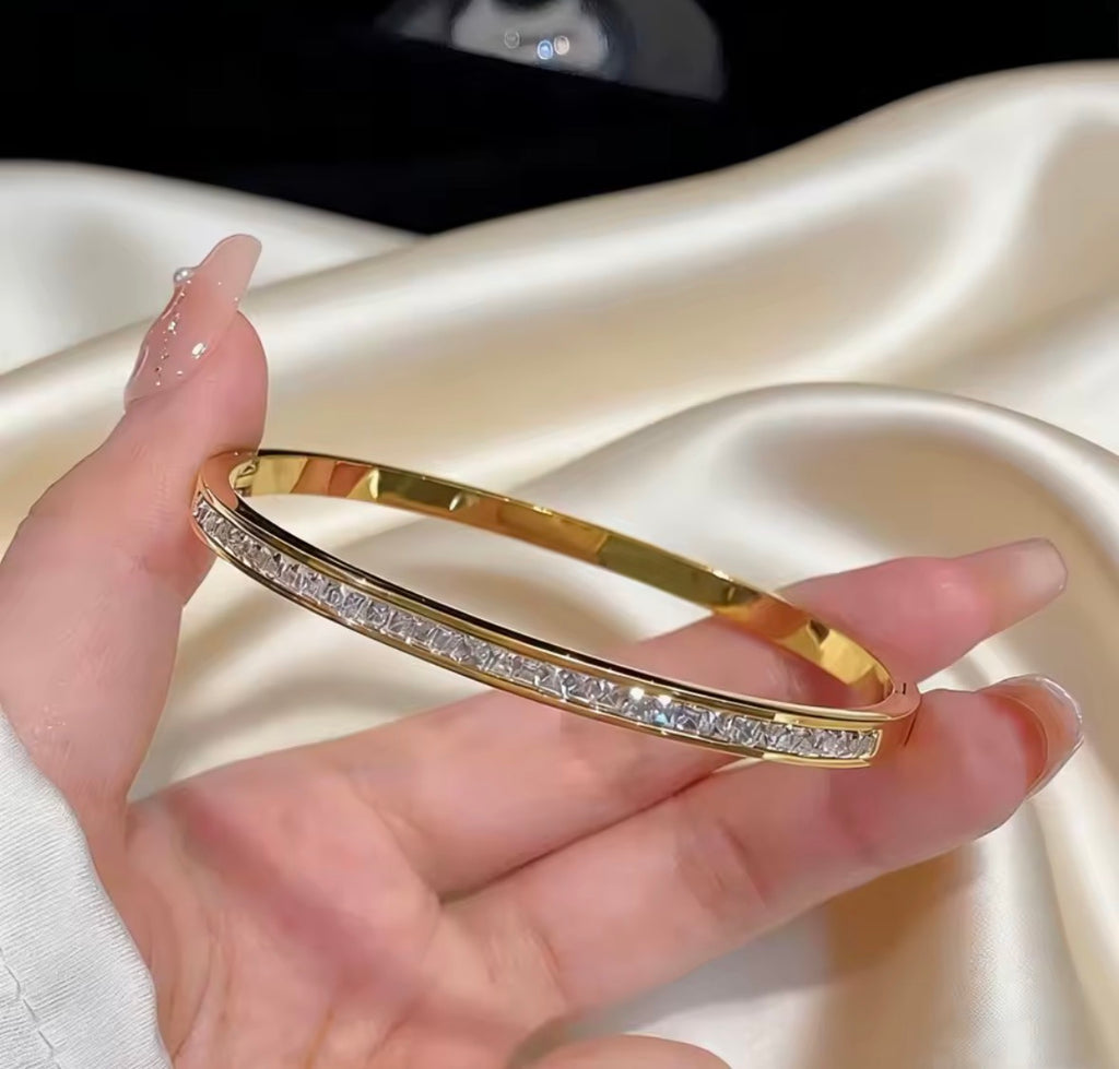 The Éclat Cuff bracelet with diamonds on a hand against a satin background