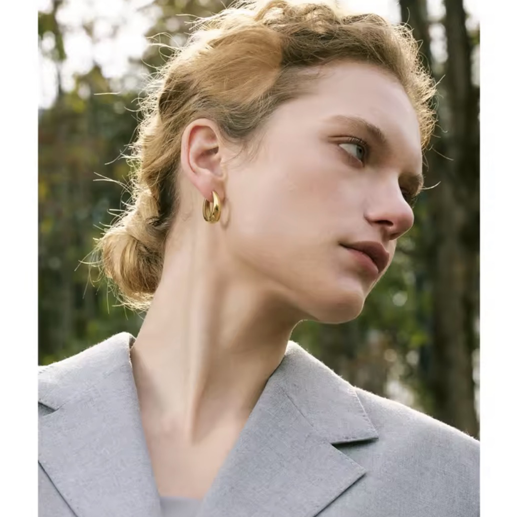 Woman wearing Nova Hoops waterproof gold geometric hoop earrings with a minimalist everyday outfit.