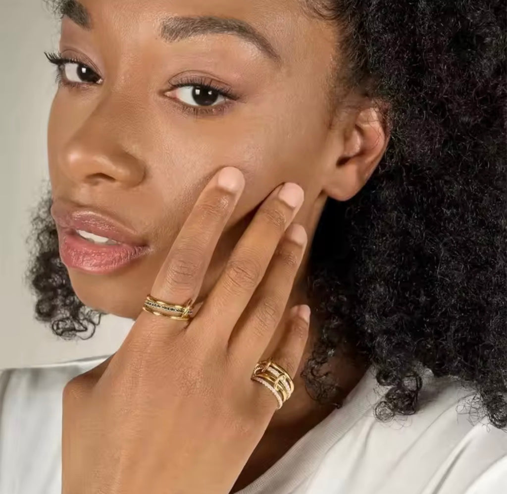 Woman with curly hair wearing Collage of hands wearing  The Harmony Ring Set on fingers on a neutral background
