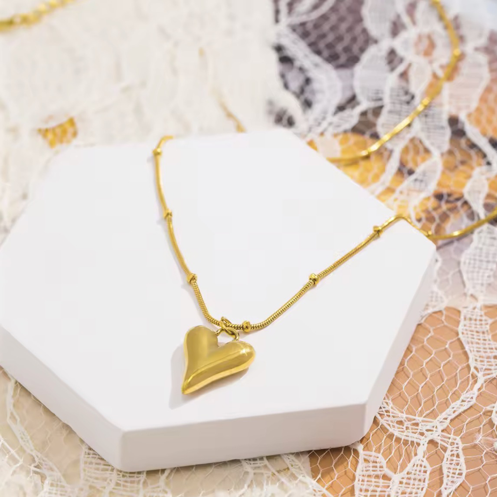 Gold heart-shaped pendant necklace on a white box with lace background