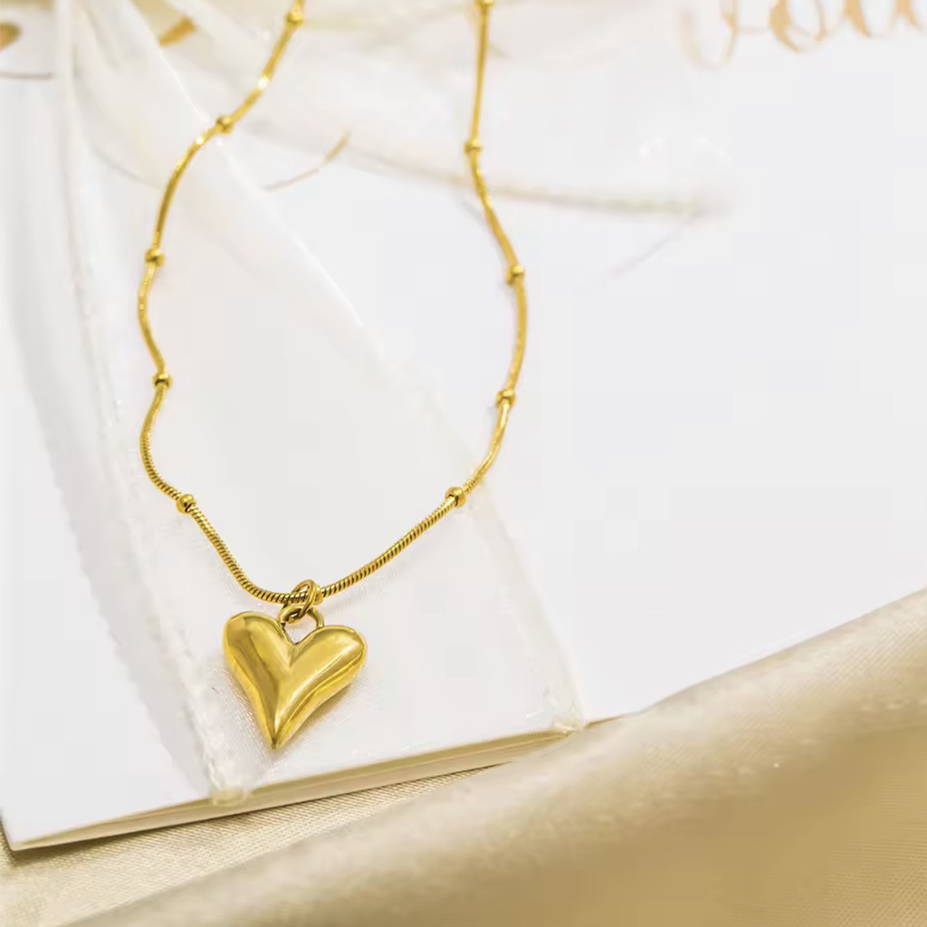 Gold heart-shaped pendant necklace on a white surface